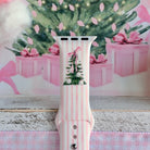 Close-up of the Pretty in PinkMas Apple Watch band print: a Christmas tree with white ornaments and a pink ribbon bow on pink stripes