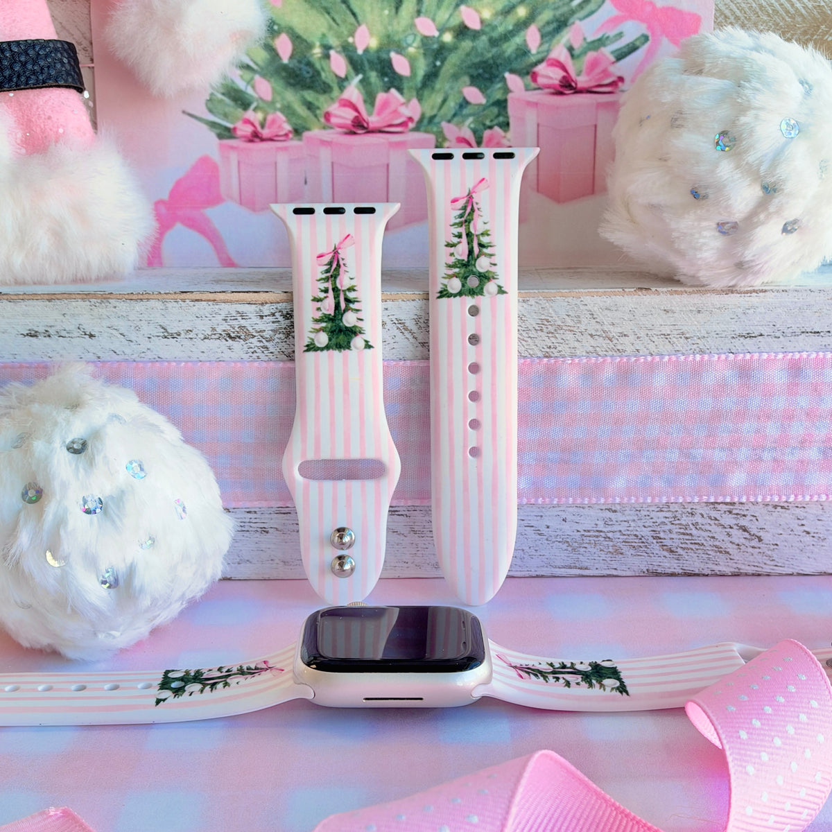 Pretty in PinkMas Apple Watch band in pink stripes with bow-tied Christmas trees, shown as two straps and on an Apple Watch, in front of pink gift boxes