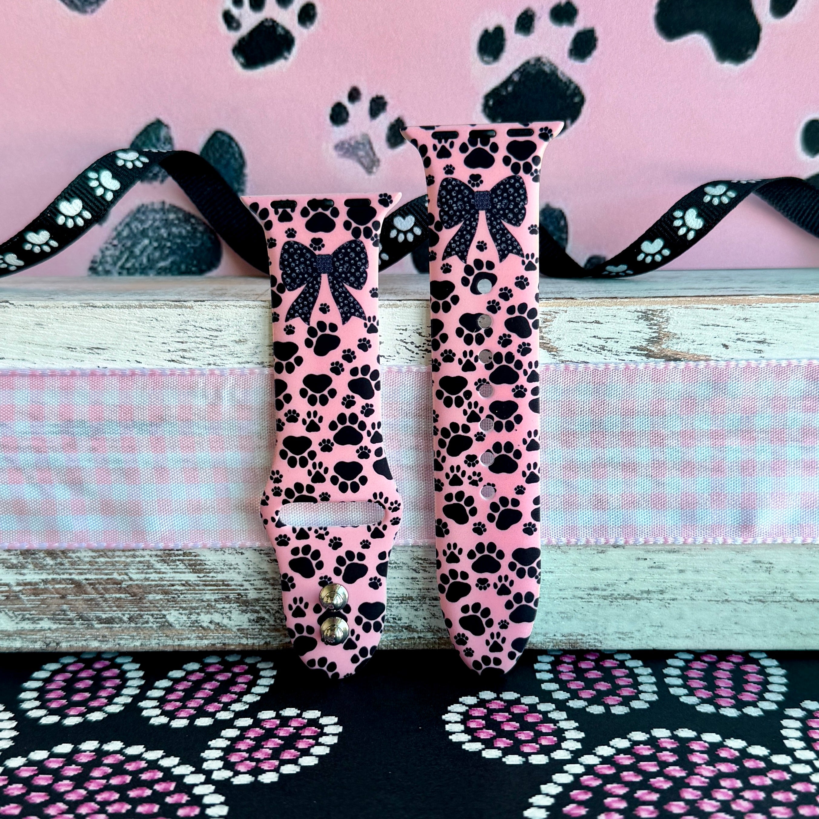 Pretty Little Paws Apple Watch band with black paw prints and polka dot bow on pink background with paw decorations
