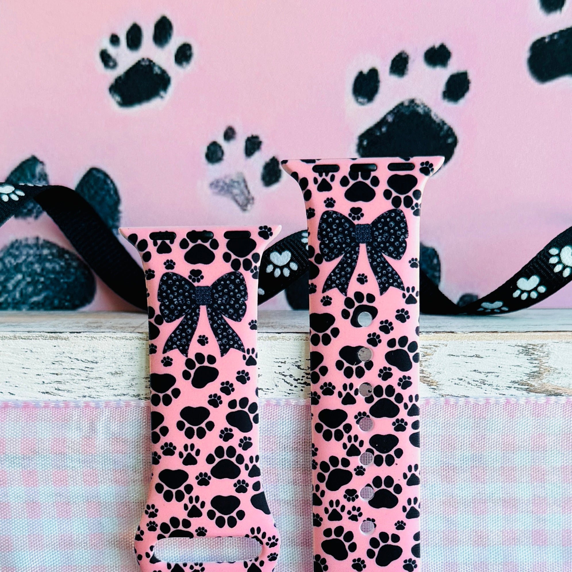 Pretty Little Paws Apple Watch band with black paw prints and polka dot bow on pink background with paw decorations
