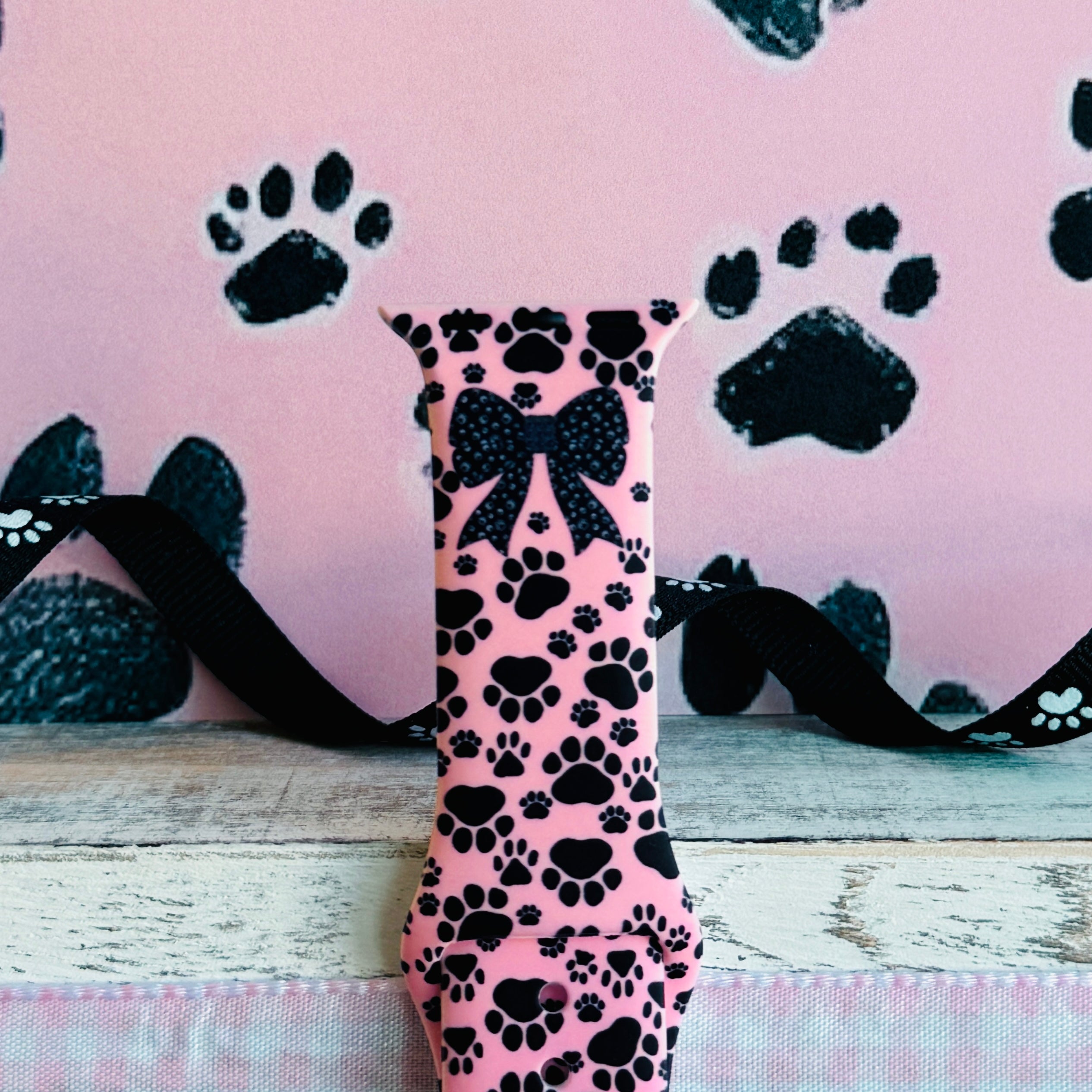 Pretty Little Paws Apple Watch band with black paw prints and polka dot bow on pink background with paw decorations
