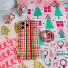 Merry Little Plaid MagSafe grip ring beside the matching iPhone case on pink and mint Christmas wrapping paper
