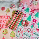 Merry Little Plaid iPhone case with the matching plaid MagSafe grip ring on a pink and mint Christmas tree backdrop