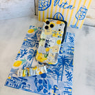 La Dolce Summer scrunchie phone wrist strap laid out with the matching Mediterranean lemon Wavy Luxe iPhone case