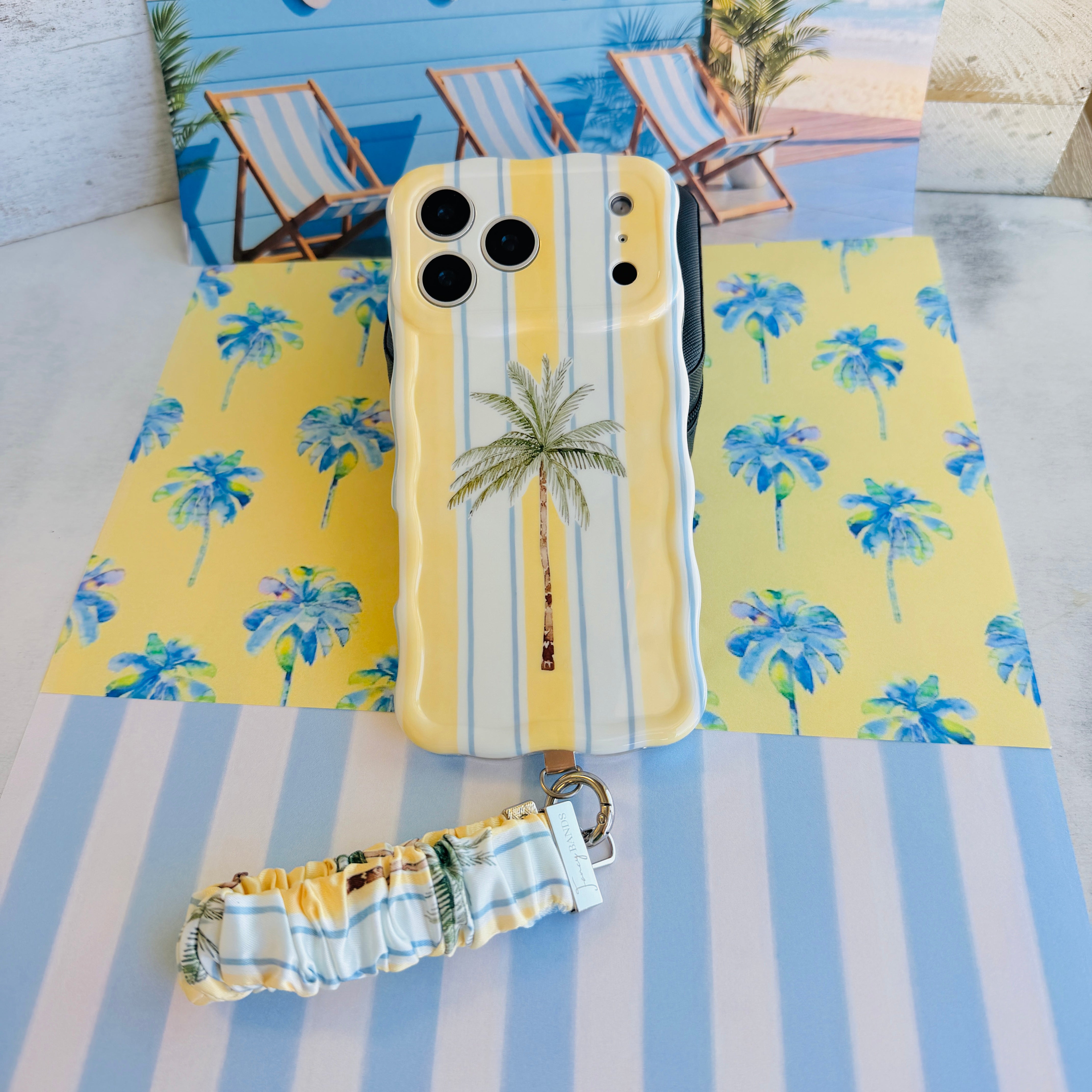Palm Shore Club scrunchie phone wrist strap clipped to the matching Palm Shore Club Wavy Luxe iPhone case