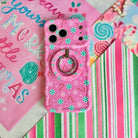Peppermint Cutie pink peppermint MagSafe grip ring snapped onto the matching iPhone case, on a Merry Little Christmas sign