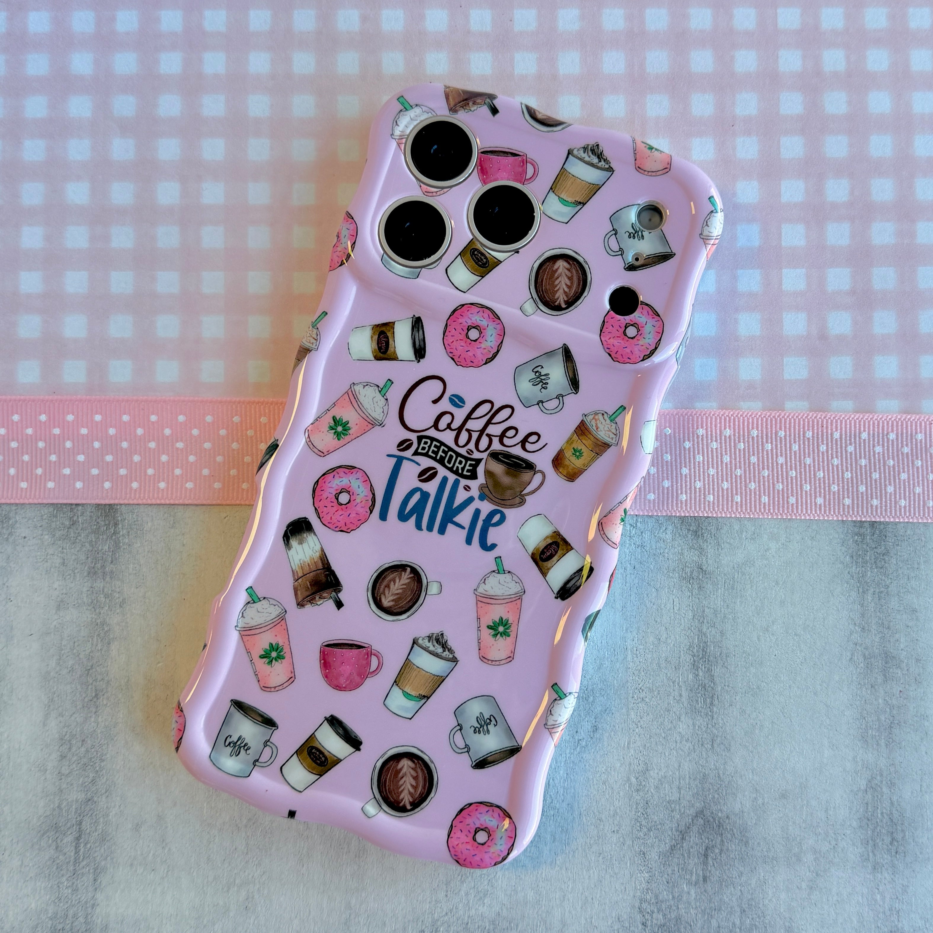 Pink phone case with coffee-themed design on a checkered background
