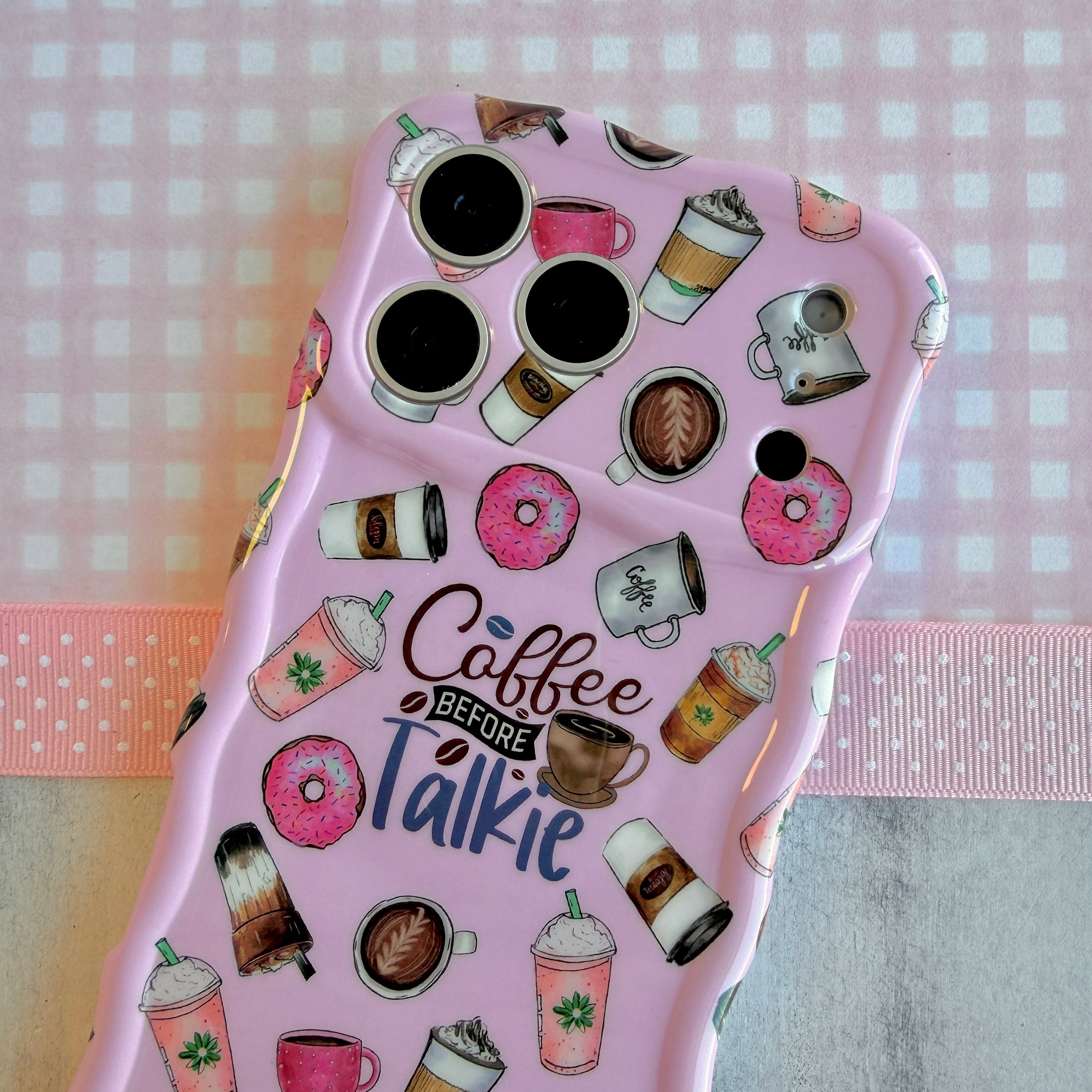 Pink phone case with coffee and donut designs on a checkered background