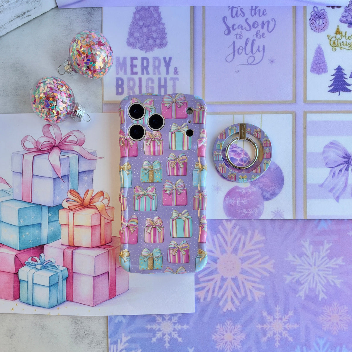 No Peeking, Darling Hold It Fancy MagSafe grip ring beside the matching pastel present iPhone case and a stack of wrapped gifts