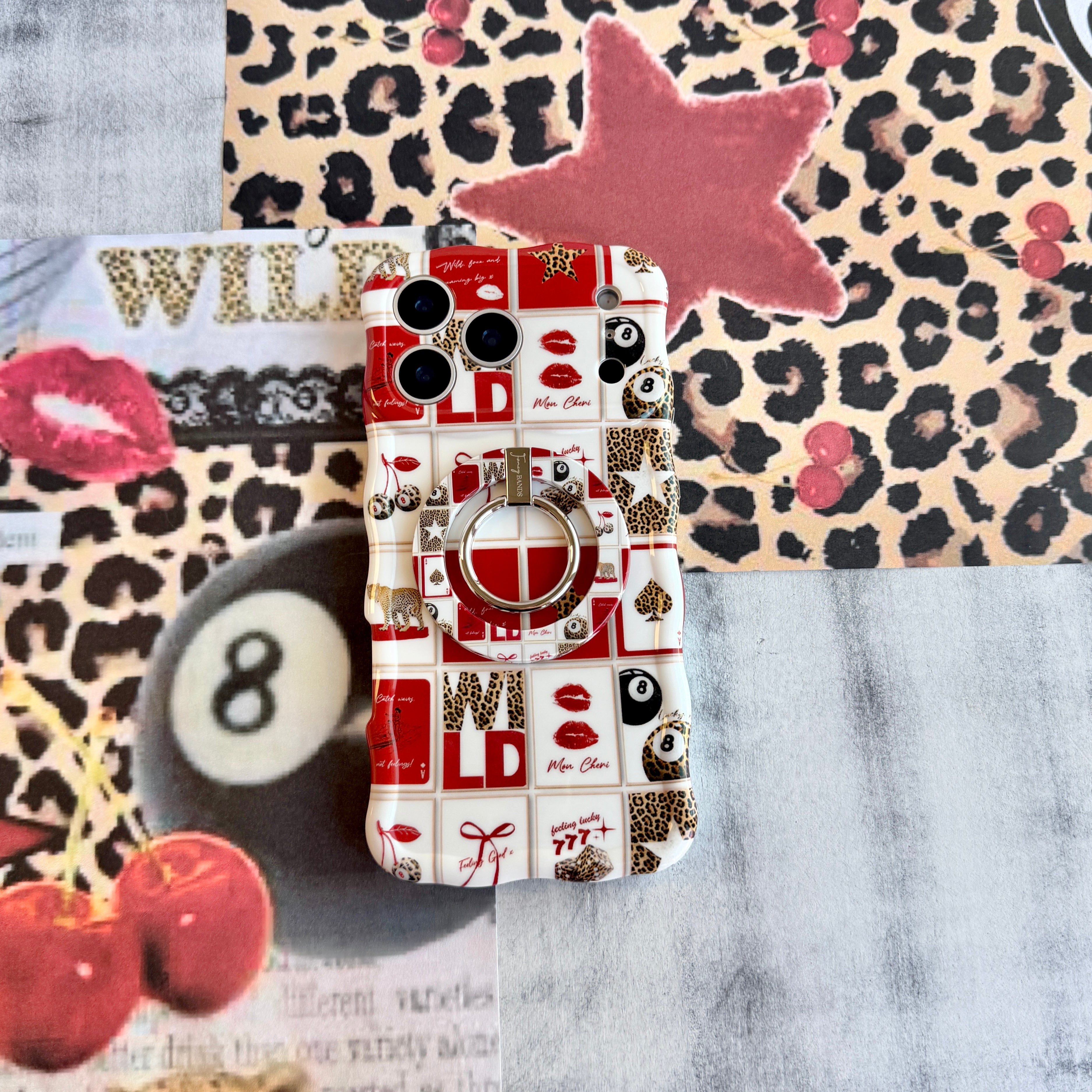 Trendy red and white wavy iPhone case featuring a collage of leopard print cherries, 8-balls, red lips, and lucky 777 dice with a high-gloss finish.