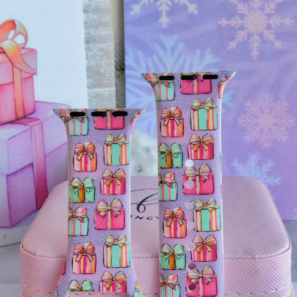 Close-up of both No Peeking, Darling Apple Watch band straps, pastel pink, aqua and striped gift boxes with gold bows