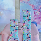 Close-up of both Twinkle All The Way Samsung Galaxy Watch band straps with pastel Christmas string lights on aqua