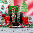Plaid Tidings & Bows Apple Watch band shown on an Apple Watch and as two straps on a black jewelry box, red bows on green gingham
