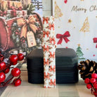 Deck Yourself in Bows & Holly Samsung Galaxy Watch band buckled and standing on a black jewelry box between red berries and a pinecone