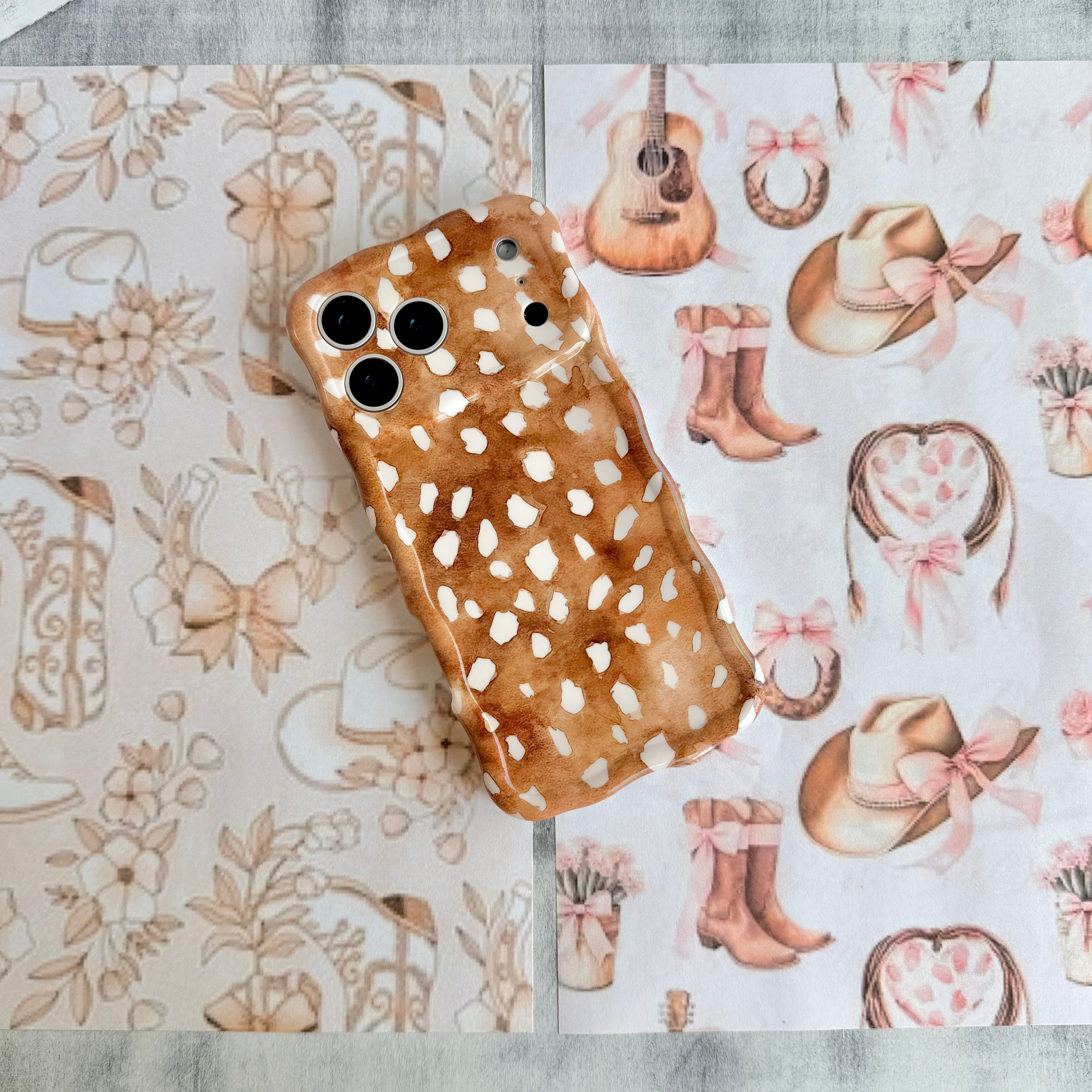 Warm whiskey-brown wavy iPhone case featuring a white fawn-spotted pattern with a high-gloss finish.