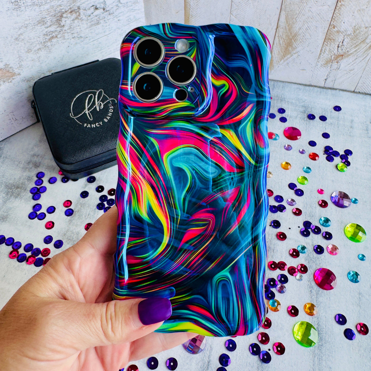 Hand holding the Neon Taffy Wavy Luxe MagSafe iPhone case, swirled neon marble in hot pink, cyan, lime and violet