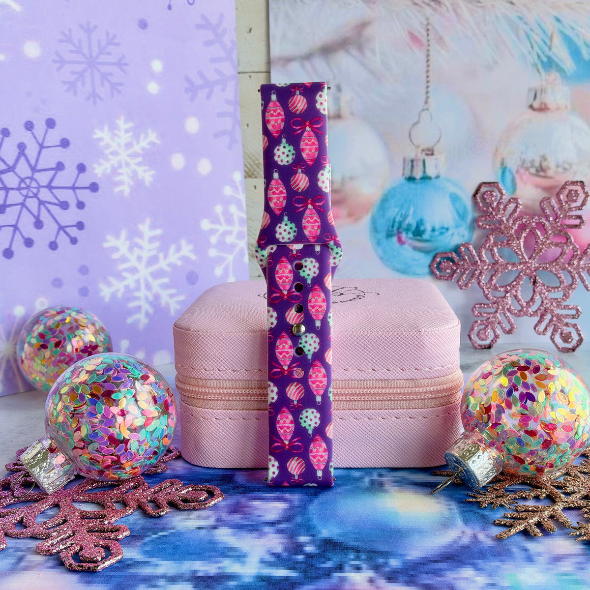 Single Just One More Ornament Samsung watch band strap standing on a pink jewelry box with aqua and pink glass ornaments behind