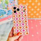 Trendy wavy iPhone case featuring a pink and orange starburst geometric pattern on a cream background with a high-gloss finish.