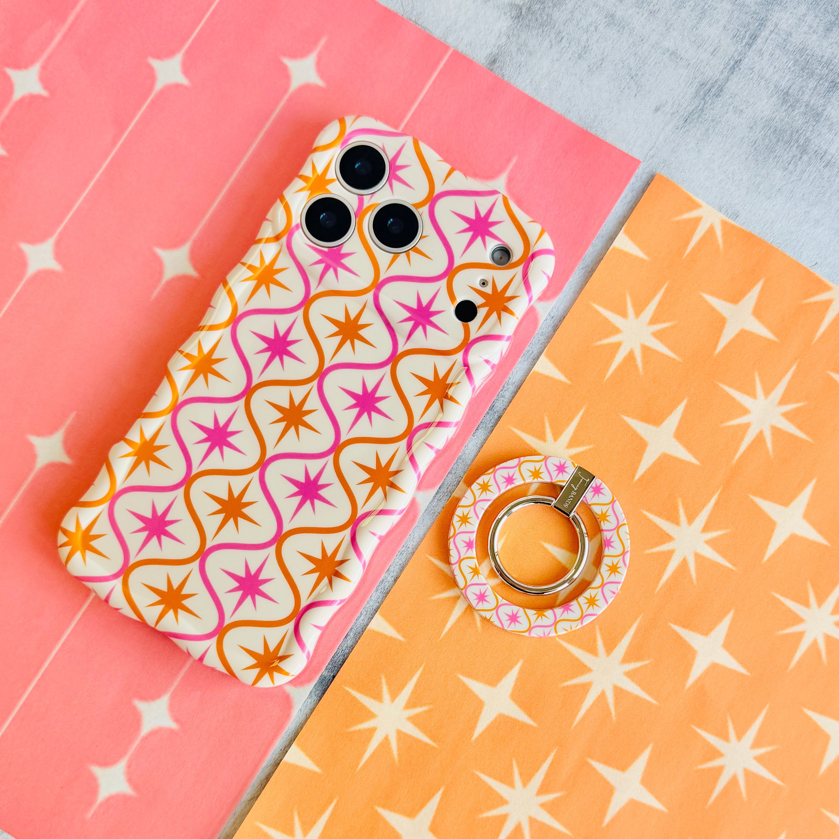 Desert Starburst retro mid-century MagSafe phone grip ring with pink and orange starbursts on a cream background compatible with iPhone and Samsung