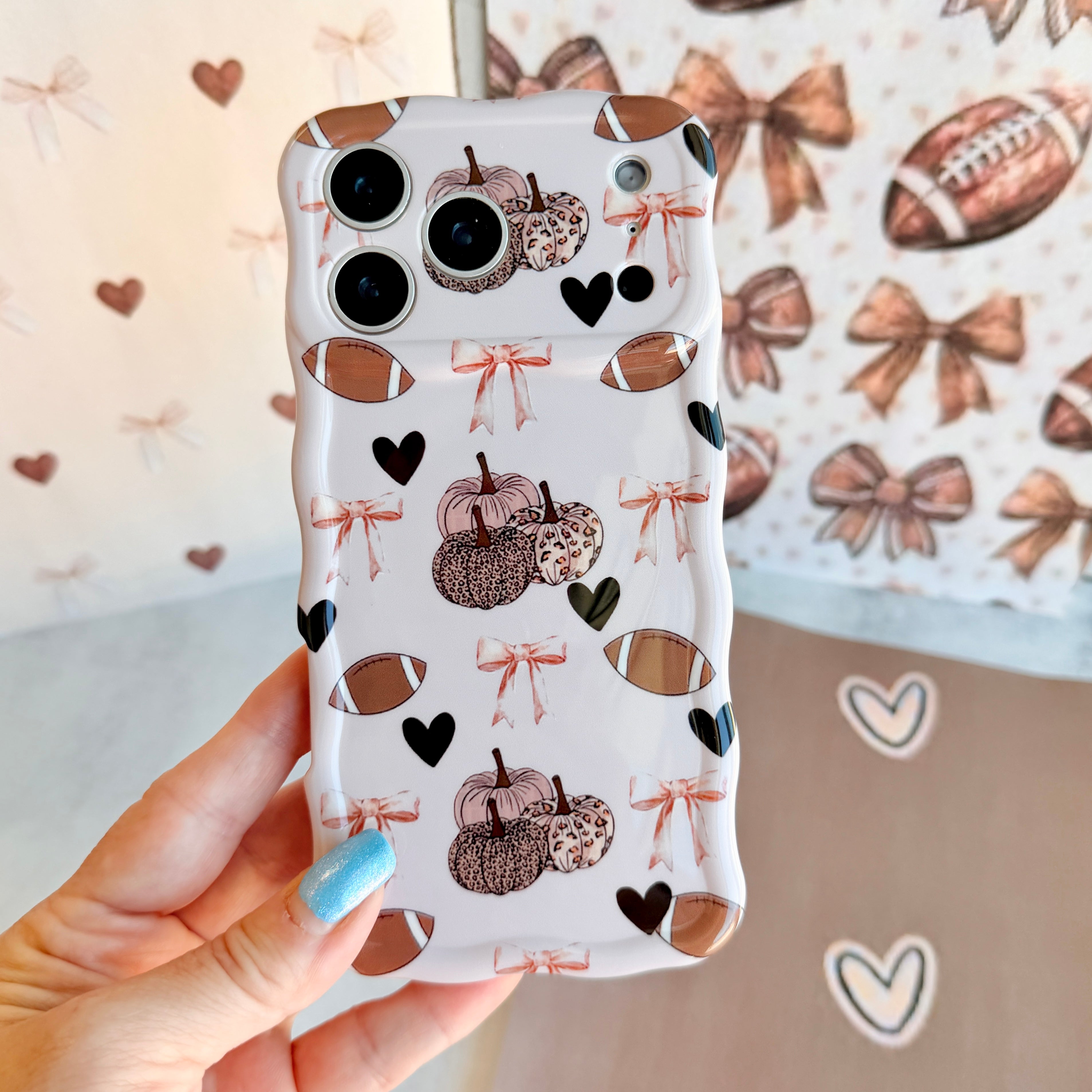 Game Day Darling Wavy Luxe MagSafe iPhone case with a cream coquette print of footballs, leopard pumpkins, bows and hearts from Fancy Bands