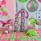 Both straps of the Merry & Bright, Totally! silicone Samsung Galaxy Watch band on a pink jewelry box with confetti ornaments and a lime bow