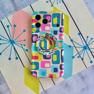 Mod Mood Hold It Fancy MagSafe grip ring attached to the matching Mod Mood iPhone case on a mid-century starburst print