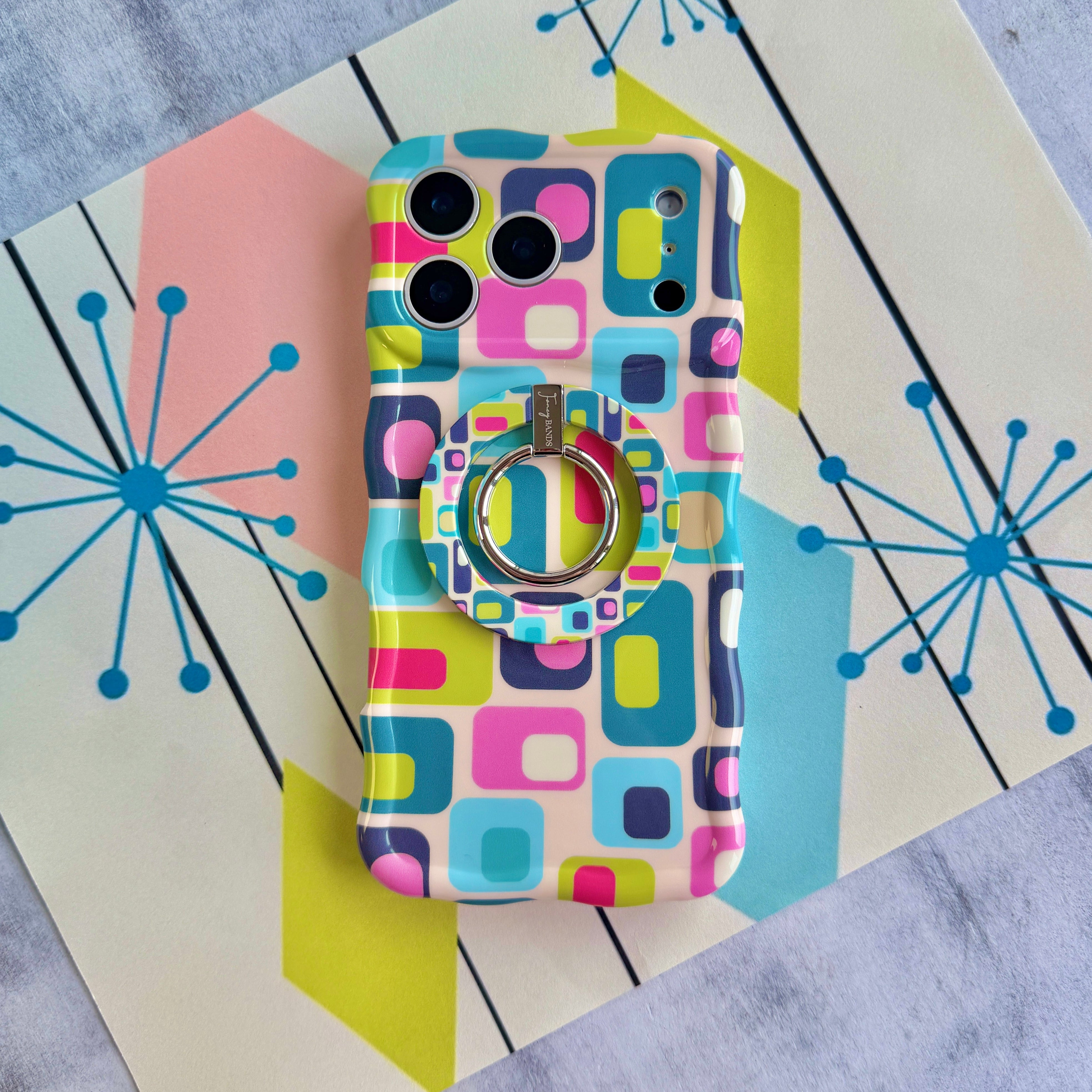 Mod Mood Hold It Fancy MagSafe grip ring attached to the matching Mod Mood iPhone case on a mid-century starburst print