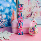 Single Sugarplum Square Apple Watch band strap standing on a pink jewelry box with a pink bottle-brush tree and snowy village backdrop