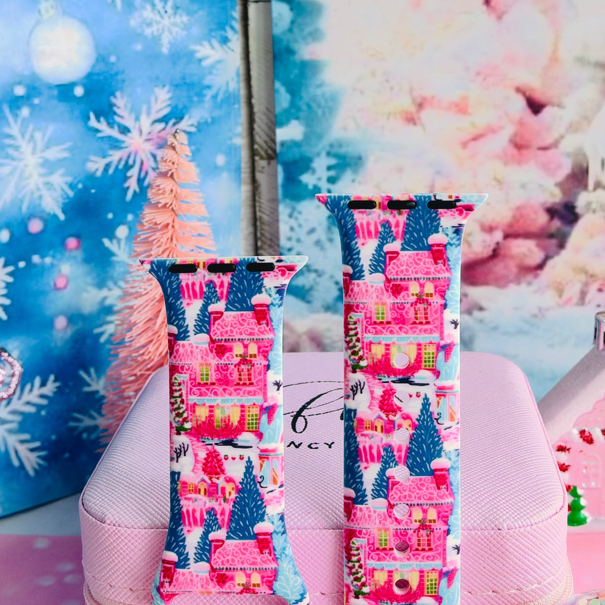Close-up of both Sugarplum Square Apple Watch band straps with pink gingerbread houses, frosted rooftops and blue pines