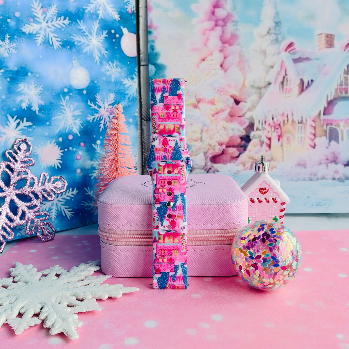 Single Sugarplum Square Samsung watch band strap standing on a pink jewelry box with white snowflakes and a confetti ornament