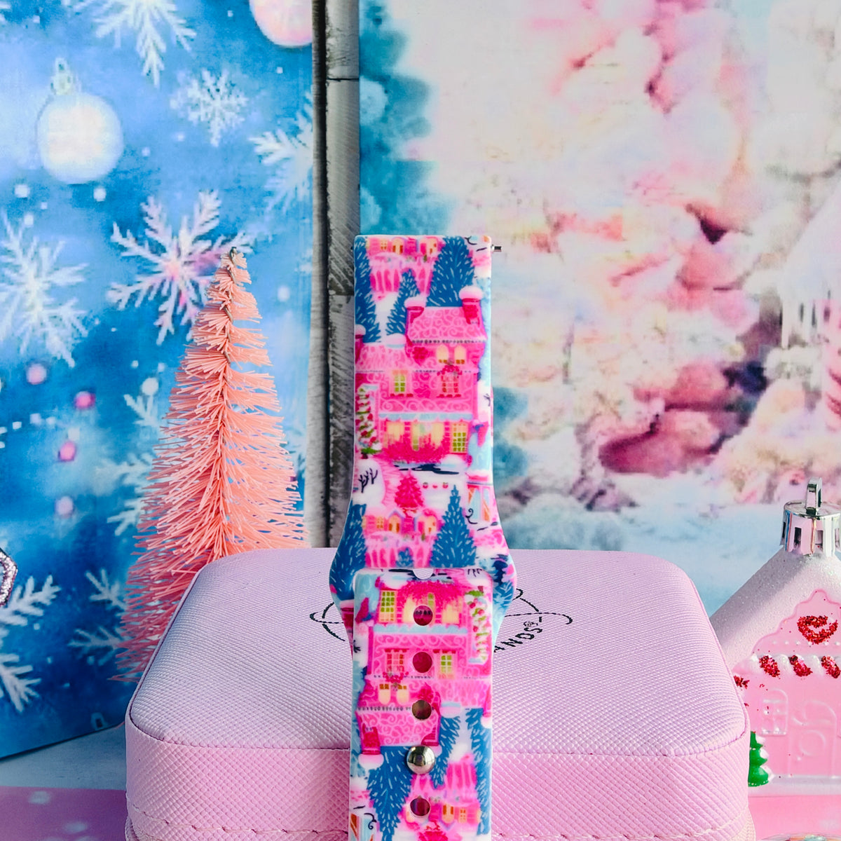 Close-up of a single buckled Sugarplum Square Samsung watch band strap on a pink jewelry box, pink Christmas village print