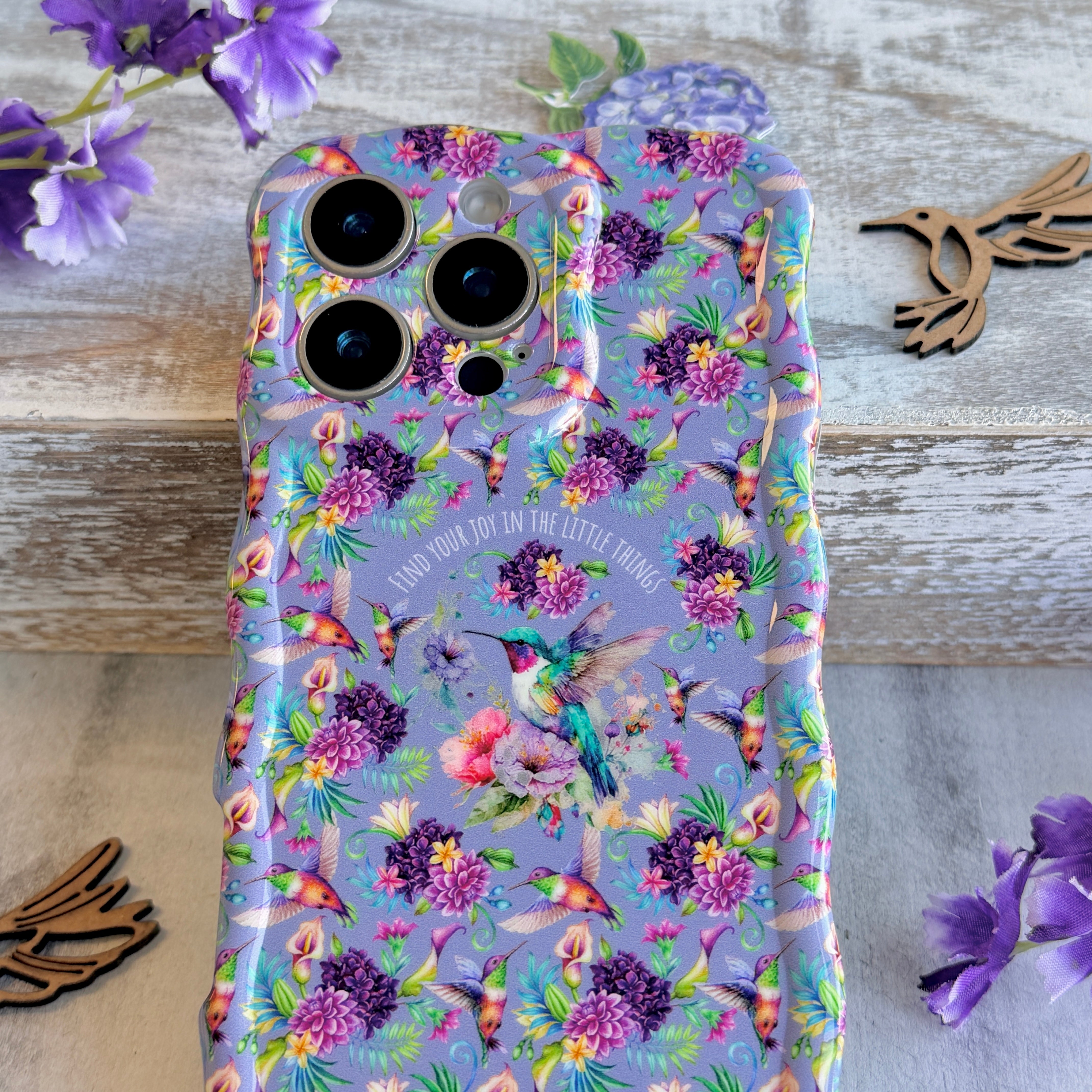Lavender wavy iPhone case featuring colorful hummingbirds, purple flowers, and the quote Find Your Joy In The Little Things.