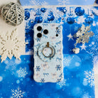 Snow Pretty In Blue MagSafe grip ring snapped onto the matching snowflake bow iPhone case, with a jingle bell and silver snowflakes on blue paper
