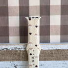 Sweater Weather Sweetheart Apple Watch band shown worn on the wrist with the cream knit, bows, and hearts print visible in daily wear context.