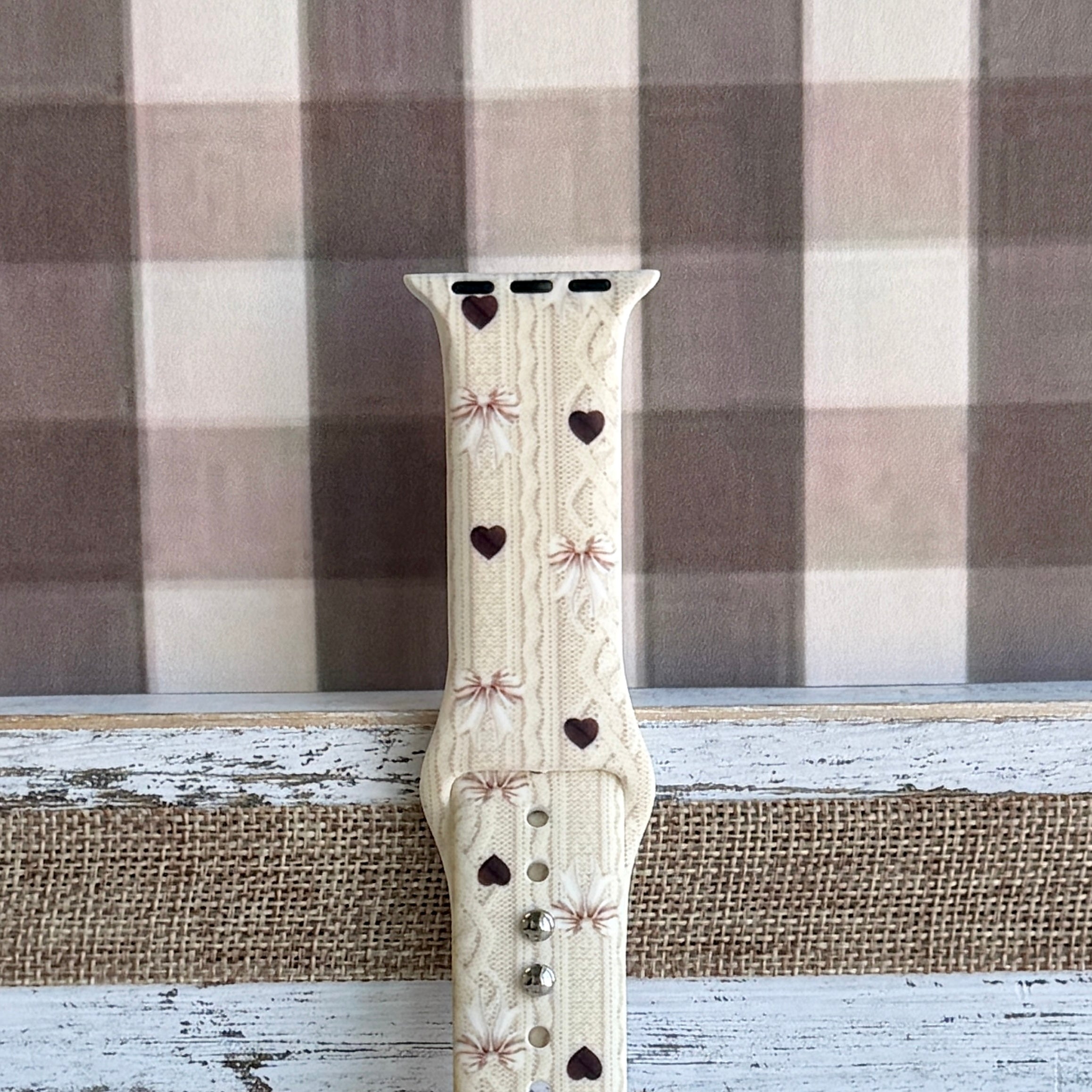 Sweater Weather Sweetheart Apple Watch band shown worn on the wrist with the cream knit, bows, and hearts print visible in daily wear context.