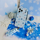 Snow Pretty In Blue iPhone case with its bow and snowflake scrunchie wrist strap, a blue gift box and a silver tinsel ball