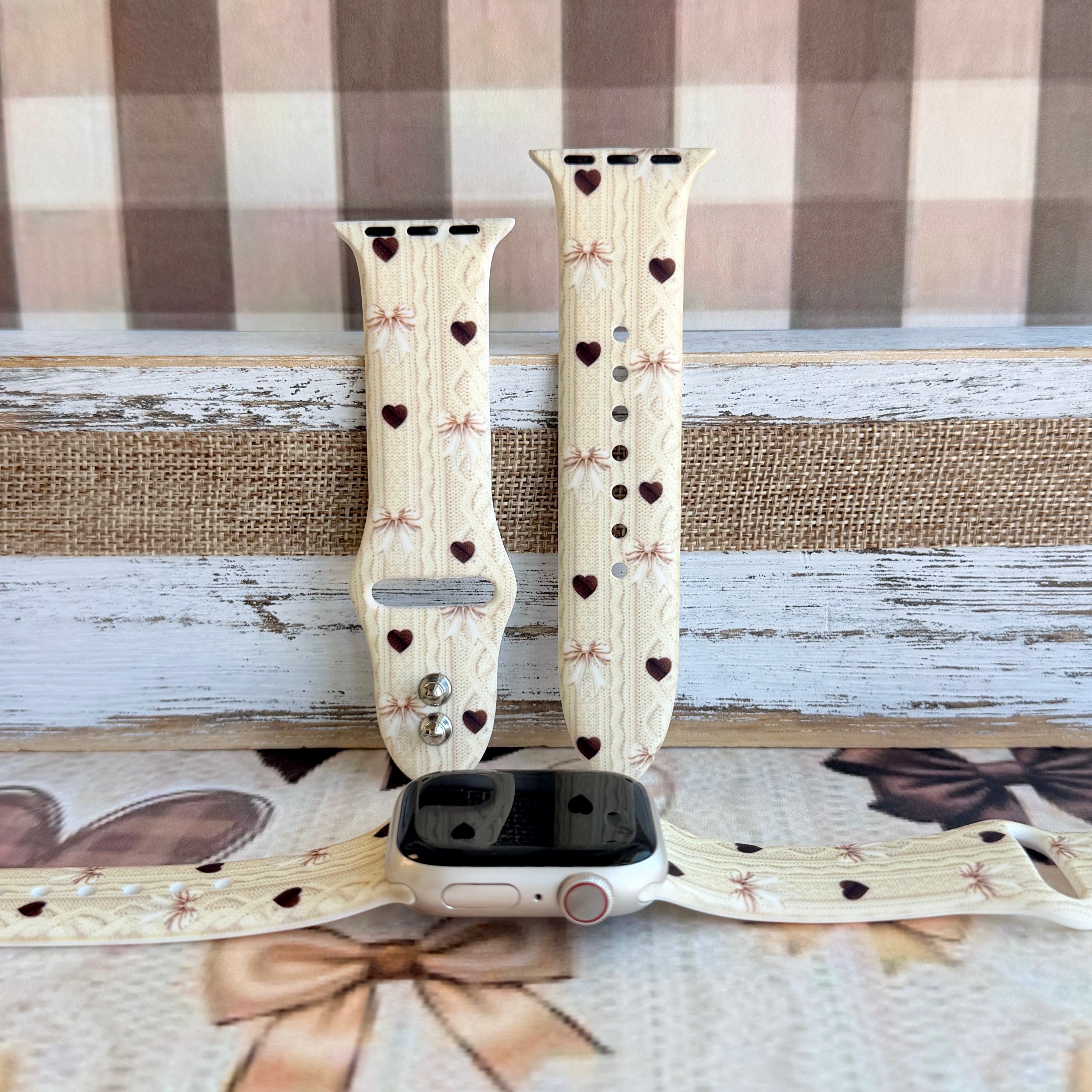 Sweater Weather Sweetheart silicone Apple Watch band featured hero shot with cream cable-knit texture, taupe bows, and rich brown hearts from Fancy Bands.