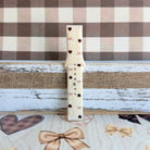 Close-up detail of Sweater Weather Sweetheart Samsung Galaxy Watch band showing the cream cable-knit texture, taupe bow print, and brown heart accents.