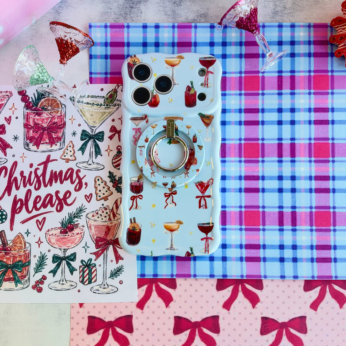 Holiday Spirits, Please? MagSafe grip ring snapped onto the matching cocktail print iPhone case, on pink and blue plaid