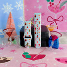 Both straps of the Holiday Spirits, Please? Samsung Galaxy Watch band on a jewelry box with a pink bottle-brush tree and a blue gift