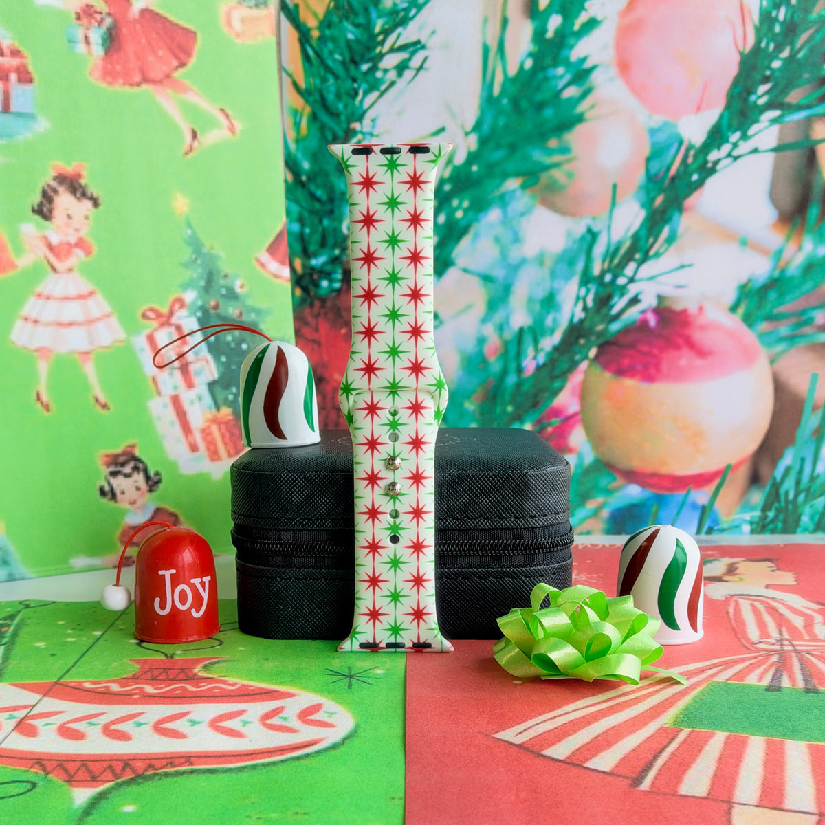 Tinsel & Stardust Apple Watch band buckled and standing on a black jewelry box with a Joy ornament and a lime green gift bow