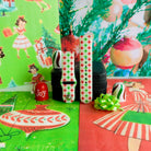 Both straps of the Tinsel & Stardust Samsung watch band on a jewelry box with a Joy ornament and a lime green bow