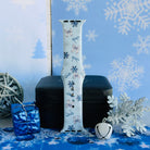 Snow Pretty In Blue Apple Watch band buckled and standing on a jewelry box beside a white jingle bell and a silver glitter snowflake