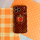 Spotted Looking Cute MagSafe grip ring attached to the matching Spotted Looking Cute iPhone case, styled flat on orange gingham and polka dot fall decor.