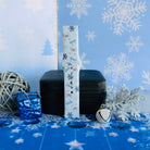 Single buckled Snow Pretty In Blue Samsung watch band strap standing on a jewelry box with a blue gift and a silver glitter snowflake