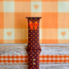 Close-up of the Spotted Looking Cute Apple Watch band showing the crisp orange and red bow artwork, pumpkin-orange dots, and the adjustment pin holes.