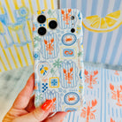 Hand holding the Coastal Catch Wavy Luxe MagSafe iPhone case with lobsters, crabs and blue tiles on a striped background