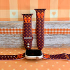 Spotted Looking Cute silicone Apple Watch band shown with an Apple Watch, both strap halves standing upright to display the chocolate brown base, pumpkin-orange polka dots, and orange bow.