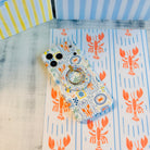 Coastal Catch MagSafe phone grip ring with orange lobster, blue stripes, and nautical postage stamp pattern compatible with iPhone and Samsung