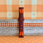 Spotted Looking Cute Samsung Galaxy Watch band full-length strap half on weathered wood and orange gingham, showing the bow detail and polka dot print end to end.
